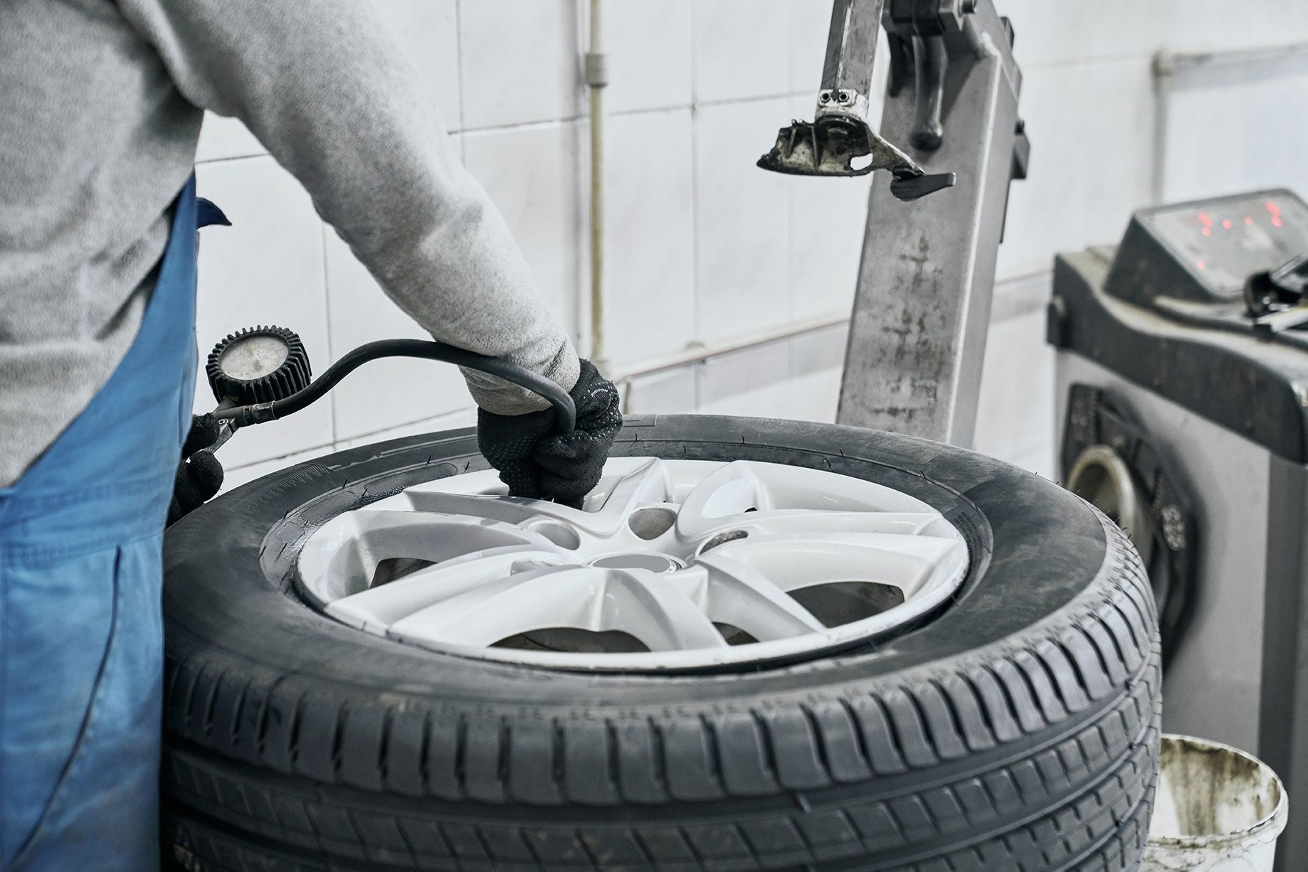 auto-mechanic-inflating-tire-and-checking-air-pres