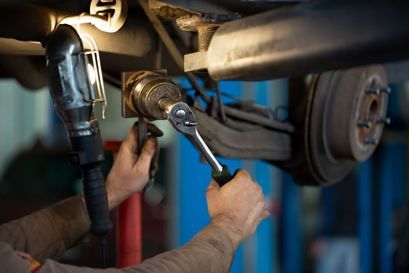 car-mechanic-worker-repairing-suspension-of-lifted