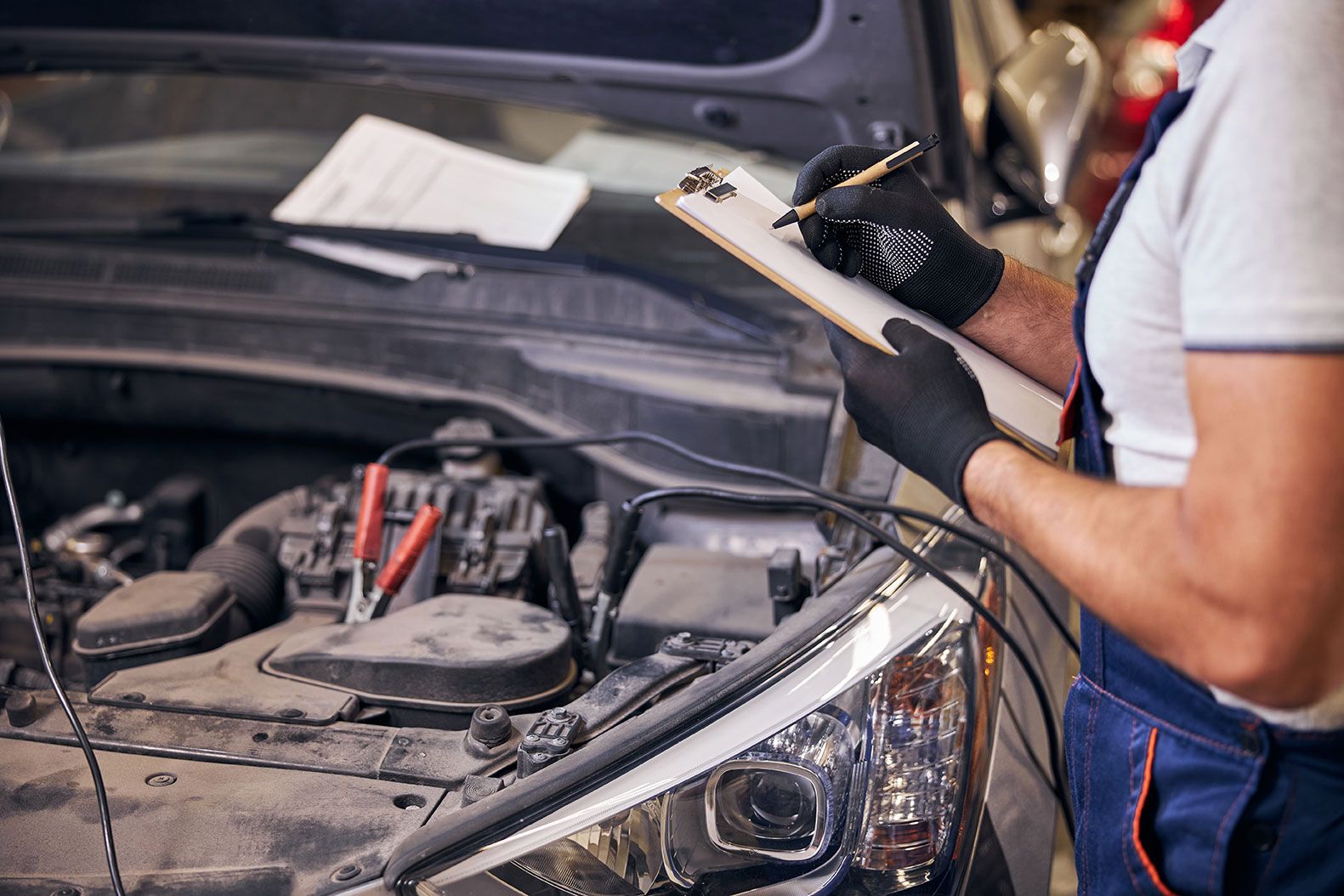 auto-mechanic-writing-on-clipboard-in-automobile