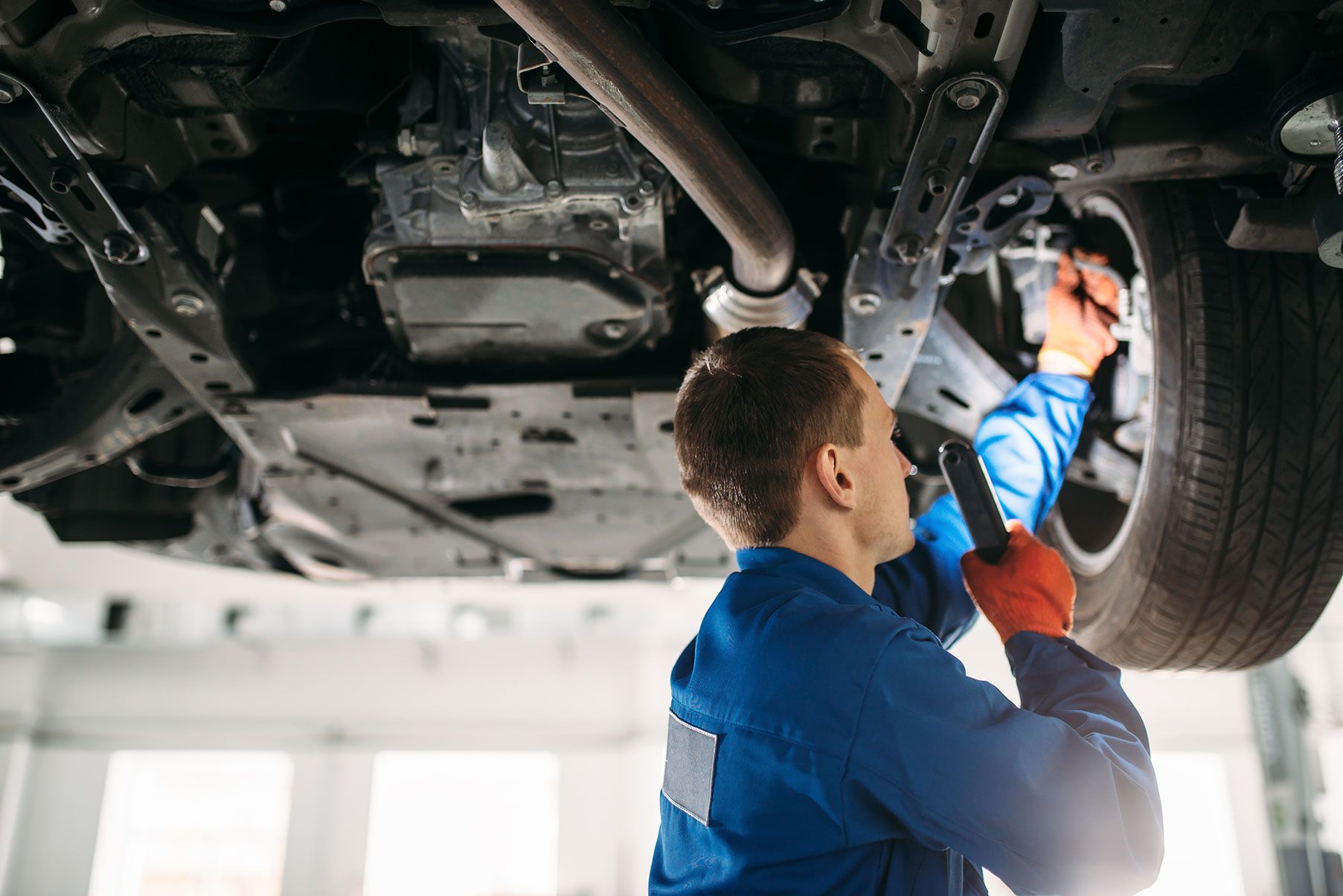 mechanic-with-lamp-checks-car-brake-hoses